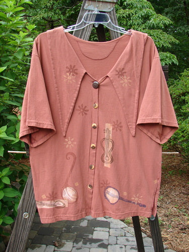 1994 Compass Top Mixed Terra Size 2, featuring an exaggerated elongated collar and vintage buttons, displayed on a hanger outdoors. The top includes side vents and a garden creature theme design.