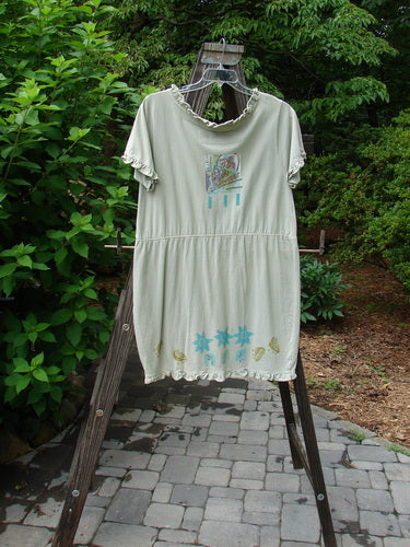 1991 Short Milkmaid Dress Sun Star Sage OSFA hanging on a rack, featuring a unique center bell shape, laced neckline, and sleeve line with a star and veggie theme pattern.