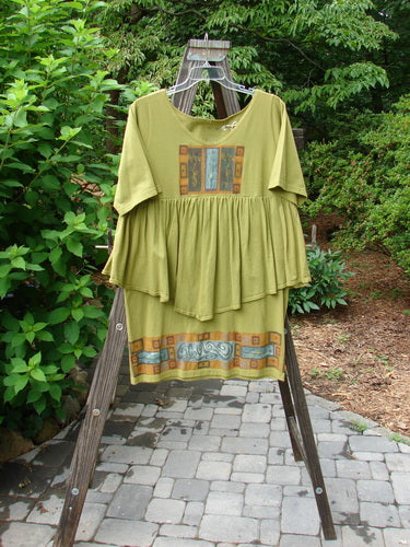 1993 NWT Picnic Dress Structural Olive OSFA displayed on a wooden ladder, featuring a gently rounded V neckline and a flirty flounce, perfect for expressing individuality.