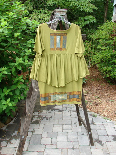 1993 NWT Picnic Dress Structural Olive OSFA displayed on a swing, featuring a gently rounded V-shaped neckline, continuous flounce, and fall-themed paint with a vintage signature patch.