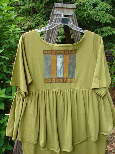 1993 NWT Picnic Dress Structural Olive OSFA displayed on a wooden swing, featuring a rounded V-neckline, continuous flounce, and fall-themed painting with a vintage signature patch.