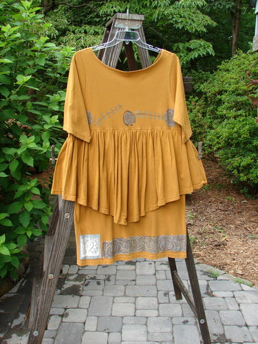 1993 Picnic Dress Windy Berries Oro OSFA displayed on a swing, featuring a gently rounded V neckline, continuous flounce, straight upper waist seam, and pencil straight shorter underpiece.