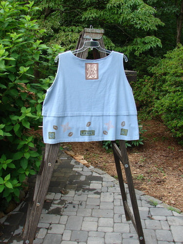 1993 Parallel Top Tiny Heart Sky OSFA displayed on a wooden easel, showcasing its crop A-line cut, rounded neckline, double-layered bodice, and distinctive Blue Fish patch.