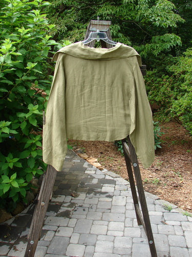 Image alt text: Barclay Linen Crop Collar Pocket Jacket in Peapod, Size 2, on a swinger with a green shirt on a rack.