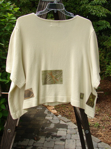 2000 Patched Recycle Jacket Science Natural Size 2 on a clothes rack, showcasing a feminine flattened rounded neckline, gently flared hemline, front squared drop pocket, and colorful bio-themed patches.