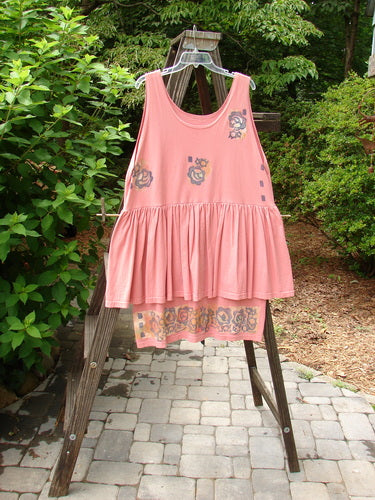 1992 Peplum Dress Floral Border Pink Clover OSFA displayed on a swing, showcasing its empire waistline, gathered lower section, and hand-dyed silk ribbon accents against an outdoor backdrop.