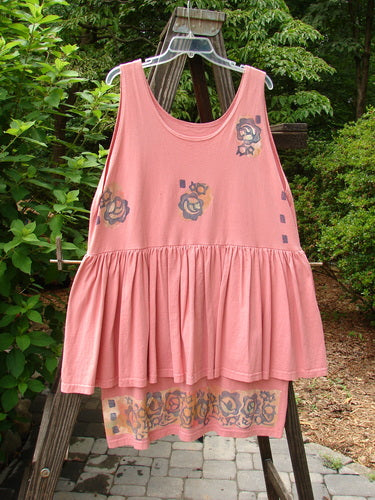 Image description: A 1992 Peplum Dress in Pink Clover with a floral border. The dress features an empire waistline, a gathered lower, and a second layer sewn into the waist. Accented by two oversized vintage buttons and hand-dyed silk ribbon. Perfect condition. Bust 48, Waist 48, Inner Piece Hip 48, Outer Flounce Circumference 100, Total Length 38.