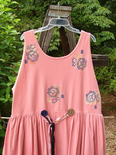 1992 Peplum Dress Floral Border Pink Clover OSFA displayed on a swing, showcasing its floral pattern, oversized vintage buttons, and empire waistline with a second layer sewn into the waist.