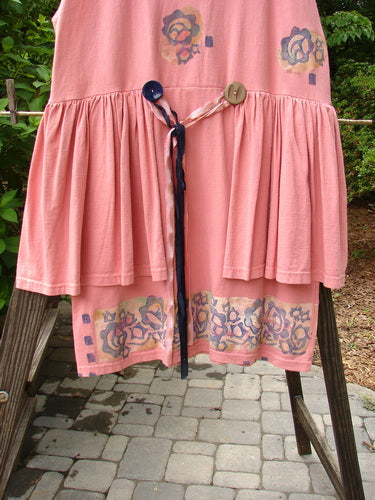 1992 Peplum Dress Floral Border Pink Clover OSFA displayed on a wooden stand, featuring an empire waistline, mega gathered lower, and adorned with oversized vintage buttons and hand-dyed silk ribbon.