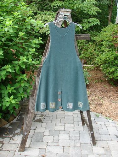 1994 Vent Vest Sweater Jumper Mixed Theme Lichen OSFA displayed on a wooden rack, showcasing its detailed hemline, clay buttons, and slenderizing A-line shape.