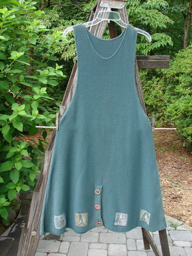 1994 Vent Vest Sweater Jumper Mixed Theme Lichen OSFA displayed on a clothes rack, showcasing its detailed hemline, 3 clay buttons, and slenderizing A-line shape with generous hip flair.