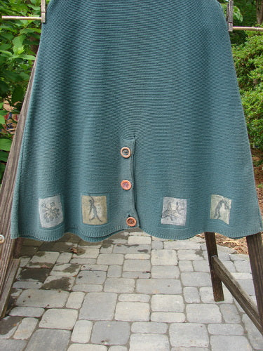 1994 Vent Vest Sweater Jumper in Lichen, OSFA: A green skirt with buttons on it, featuring a wooden fence post on a stone walkway.