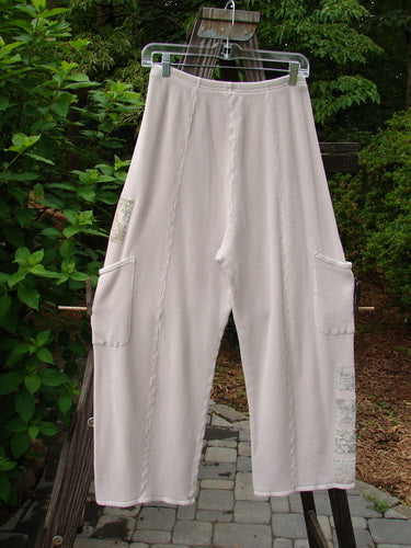Barclay Thermal Patched Pottery Pant Garden Pink Cloud Size 1 hanging on a clothesline, showcasing full elastic waistline and exterior pockets with vertical stitchery and painted garden patches.