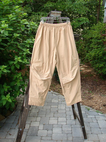 A pair of 2000 Parachute Trekker Pant Unpainted Carmel Size 2, displayed on a clothes rack, showcasing their sturdy, medium-weight cotton fabric with additional knee patches and a full elastic waistline.