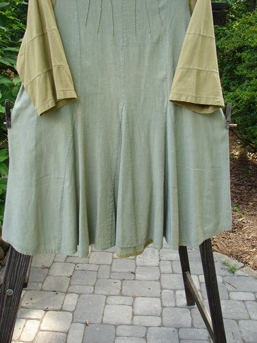 Barclay Playdate Sunrise Spin Dress Unpainted Spice Size 1 on a rack, showcasing a rolled neckline with raised sunrise pleats and a mega sectional skirt with contrasting fabrics.