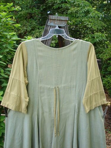 Barclay Playdate Sunrise Spin Dress Unpainted Spice Size 1 displayed on a wooden swing, showcasing its rolled neckline, sectional skirt panels, contrasting sleeve fabrics, and sweeping lower shape.