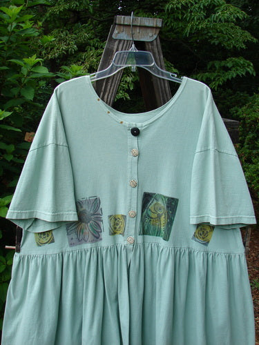 Green Tourmaline 1992 Studio Cardigan Dress with bold fish and flower design, flouncy bottom, gathered waistline, vintage buttons, and Blue Fish signature patch, displayed on a hanger.