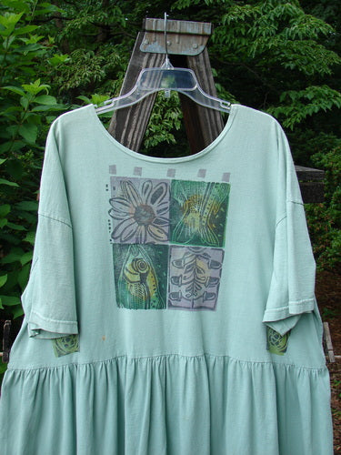 1992 Studio Cardigan Dress in Green Tourmaline with fish and flower design, featuring a dropped waist, flouncy lower front, vintage buttons, and a Blue Fish signature patch.