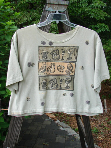 1991 Short Sleeved Oversized Tee Pitcher Glass Wheat OSFA displayed on a hanger, showcasing a wide boxy cut with a vintage goblet drawing and blue fish patch.