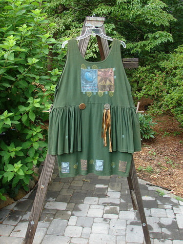 1992 Peplum Dress Sun Moon Star Evergreen OSFA displayed on a swinger, showcasing the distinctive mega gathered lower and side wrap peplum, with oversized vintage buttons and hand-dyed silk ribbon accents.
