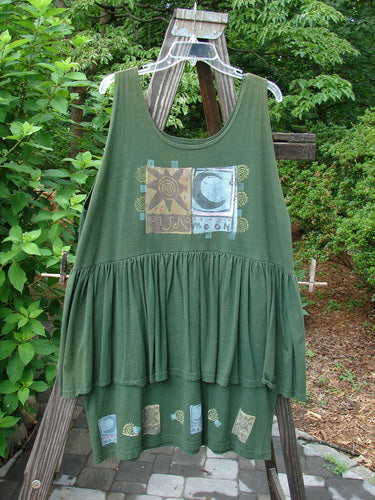 1992 Peplum Dress Sun Moon Star Evergreen OSFA displayed on a swing, featuring oversized buttons, a mega gathered lower, side wrap peplum, and hand-dyed silk ribbon accents.