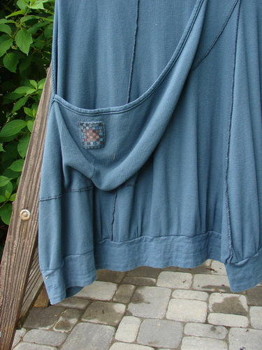 Barclay Patched Thermal Traverse Jumper Teal Size 2 on a wooden rack, showcasing its unique sectional accents, exterior seams, belled lower, deep arm openings, and a diagonal pocket.