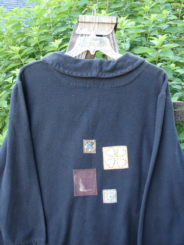 1999 Patched Flannel PJ Top Paper Doll Black Size 1, featuring thick cozy flannel, drop shoulders, vented sides, A-line shape, fold-over collar, and paper doll-themed patches on front and back.