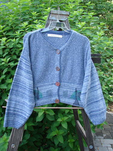 1994 Crop Cardigan Sweater Wine Bottle Haiku Blue OSFA displayed on a swing, highlighting its cozy longer sleeves, dropped shoulders, and unique stoneware buttons with a vibrant knit texture.