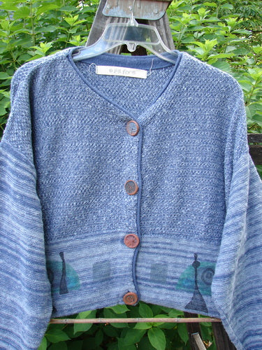 1994 Crop Cardigan Sweater Wine Bottle Haiku Blue OSFA featuring stoneware buttons, V-shaped neckline, contrasting knits, and wine bottle theme paint. Cozy longer sleeves and dropped shoulders with a rolled neckline.