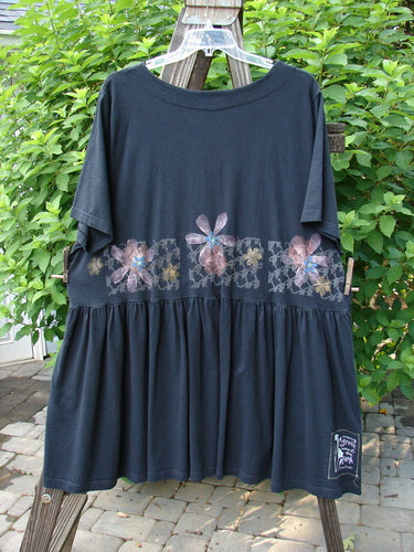 2000 Rosalee Dress Continuous Floral Black Size 2: A vintage babydoll-style dress with a sweeping lower hem, gathered waist, and continuous floral pattern on the bodice, made from organic cotton.