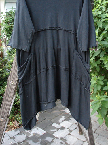 Barclay Reverse Stitch Double Pocket Tunic Dress Fern Garden Black Size 2 on a clothes rack, showcasing exterior flutter seams, lettuce-edged sleeves, varying hemline, and two drop front wrap-around pockets.