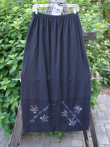 1997 NWT Indra Skirt Abstract Floral Obsidian Size 1, showcasing a long black skirt with an abstract floral design, full elastic waistline, double-paneled lower, colorful buttons, and loop closures.