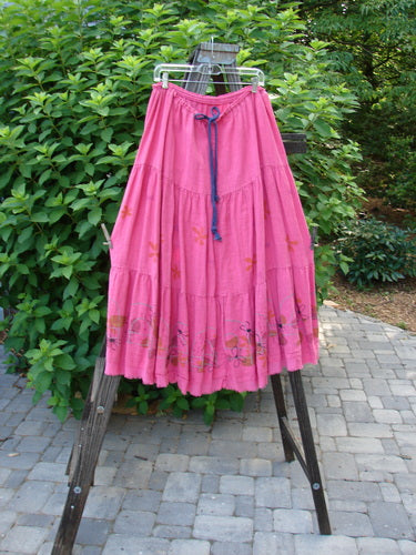 Barclay Linen Drawstring Ruffle Skirt Daisy Fence Flamingo Size 2 hanging on a rack, showcasing its full contrasting drawstring waistline, horizontal seams, A-line shape, and billowy flare with fringe edges.