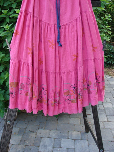 Barclay Linen Drawstring Ruffle Skirt Daisy Fence Flamingo Size 2 displayed on a rack, showcasing its full drawstring waistline, alternating horizontal seams, and A-line billowy flare with fringe edges.