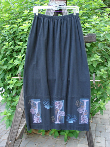 1997 Indra Skirt Whimsical Forest Obsidian Size 1 features a long black design with colorful buttons, deep side pockets, and a whimsical forest theme pattern. Made from mid-weight organic cotton.