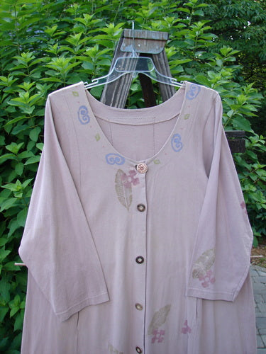 1993 Modernismo Duster Dress Columns Ash Pink OSFA displayed on a wooden stand, featuring vintage wooden buttons, a scooped neckline, kangaroo pockets, and a unique column and leaf pattern.