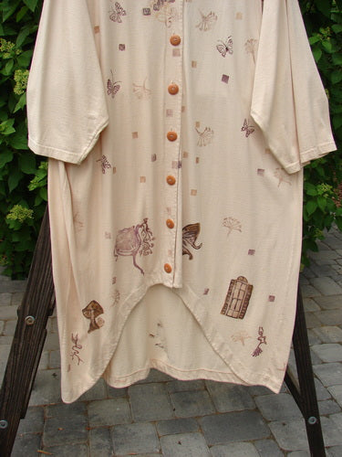 1994 Convertible Coat Spring Garden Tea Dye OSFA displayed on a hanger, showcasing its versatile button-on/off sleeves, unique scooped front hemline, and painted spring garden theme.