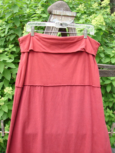 Barclay Hemp Cotton Decora Fold Over Skirt Unpainted Brick Size 2 displayed on a clothes rack, showcasing its A-line shape, full double-paneled waistline, and sweet curly edgings.