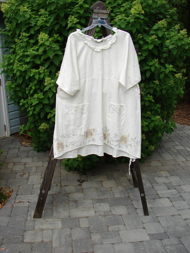 Barclay Linen Duet Sunrise Dress in Creme, featuring a sweet curly neckline, vertical pleats, and floral fern design, displayed on a clothes rack. Perfect vintage style from BlueFishFinder.com.