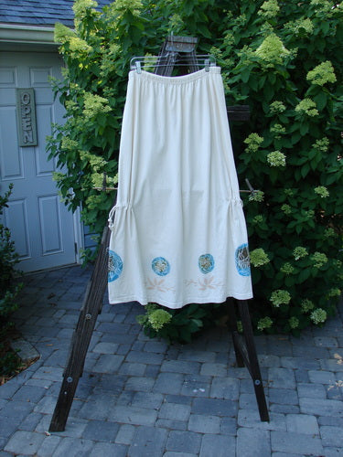 1999 Tie In Skirt Leaf Medallion Natural Size 2 on a rack, showcasing its full elastic waistband, super draw cords, and detailed leaf medallion theme paint across unique sectional panels.