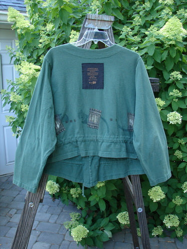 1997 Treehouse Jacket Many Windows Verdigris Size 2 displayed on a hanger, showcasing unique double-paneled V-neck, button line, signature Blue Fish patch, and front draw cord flounce.