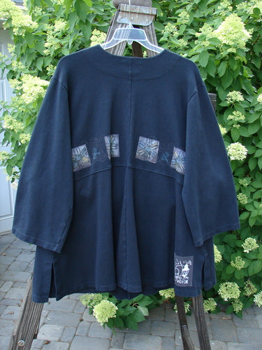 Image alt text: "1999 Interlock Stellar Jacket with Celtic Flower design, size 0, in black. Heavyweight cotton with metallic holiday paint. Features include large front pockets, vented sides, oversized buttons, bell sleeves, and empire waist seam. Signature Blue Fish patch. Densely knit with fleecy underside. Length: 34 inches."