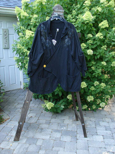 Barclay NWT Hemp Cotton Tidal Jacket Roses Black Size 2 displayed on a wooden stand, showcasing unique button closure, exterior pockets, and decorative ties, emphasizing its detailed rose pattern and intricate seam design.
