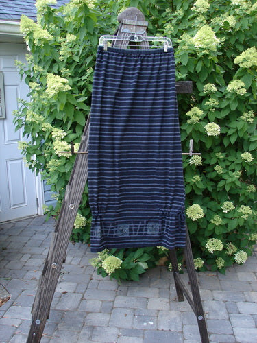1999 Stripe Box Straight Tie Duo Water Fern Black Size 2 skirt on a clothes rack, showcasing a full elastic waistline, straight pegged look, and bottom side tie accents against a blue and white striped fabric backdrop.