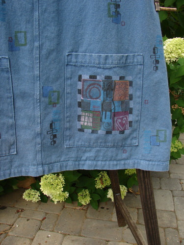 A Barclay Canvas Urban Pocket Apron Jumper featuring a patchwork design made from heavy-duty hemp twill fabric. This blue jean jacket has tear button accents, fixed shoulder straps, and two generous drop front exterior pockets. The mosaic chair theme paint adds a unique touch to this substantial piece.