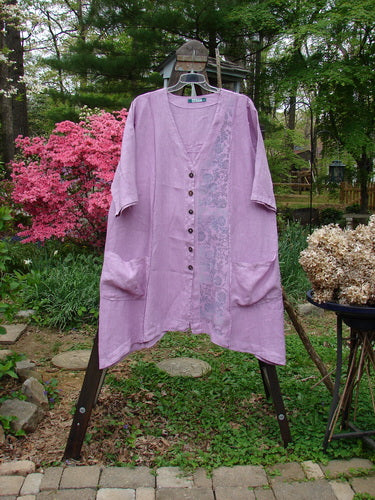 Barclay Linen Double Tie Back Jacket Garden Side Lilac Size 2 displayed on a hanger, featuring a deep V neckline, A-line sweep, vertical stitchery, drop pockets, and detailed garden-themed paint.