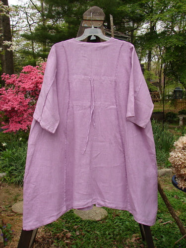 Barclay Linen Double Tie Back Jacket Garden Side Lilac Size 2 displayed hanging outdoors, showcasing its deep V-neckline, A-line sweep, front drop pockets, and detailed garden-themed paint.