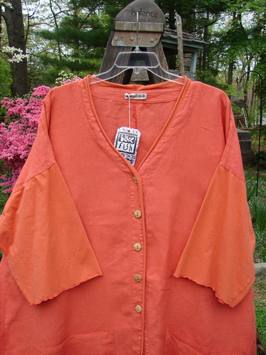 Barclay NWT Linen Cotton Sleeve Pocket Cardigan in Clementine, featuring wooden-like buttons, upward curved hemlines, V-shaped neckline, drop shoulders, and front squared-off pockets.