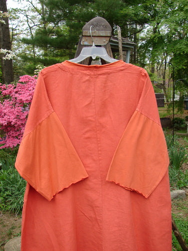 Barclay NWT Linen Cotton Sleeve Pocket Cardigan Contrast Unpainted Clementine Size 2 displayed on a hanger, showcasing wooden buttons, V-neckline, drop shoulders, and curved hemline against a blurred natural background.