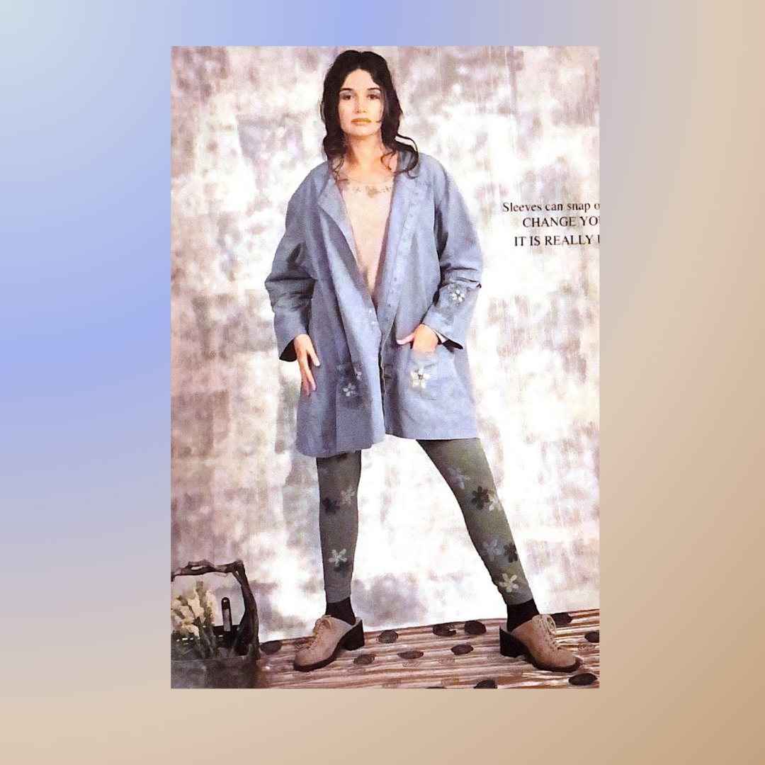 A Model displays a layered look from the spring collection of 2000. She is wearing the snap jacket coordinating legging and a cotton lycra layering top in Three blended colors. She is in the studio and has her hands in the jacket pockets.
